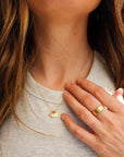 Close-up of woman wearing 14K solid gold dainty initial necklace and ring