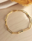 Close-up of 14K solid gold engravable bracelet with name customization on soft fabric
