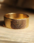 4K solid gold fingerprint band on wood surface with dramatic shadowing