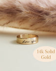 Close-up of 14K solid gold handwriting ring engraved with 'Love you' on soft blush background