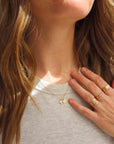 Woman styling 14K solid gold initial pendant necklace with gold stacking rings