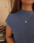 14K solid gold name necklace styled over soft blue ribbed knit top