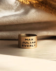 14K solid gold personalized band engraved with names resting on cozy textured fabric