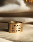 Close-up of 14K solid gold personalized band with engraved text, styled on golden fabric