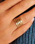 Close-up of 14K solid gold personalized band worn on model’s finger with visible engravings