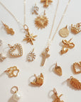Close-up of 18k gold plated PVD add-on charms on dainty gold chain featuring star, heart, sun, and pearl charms