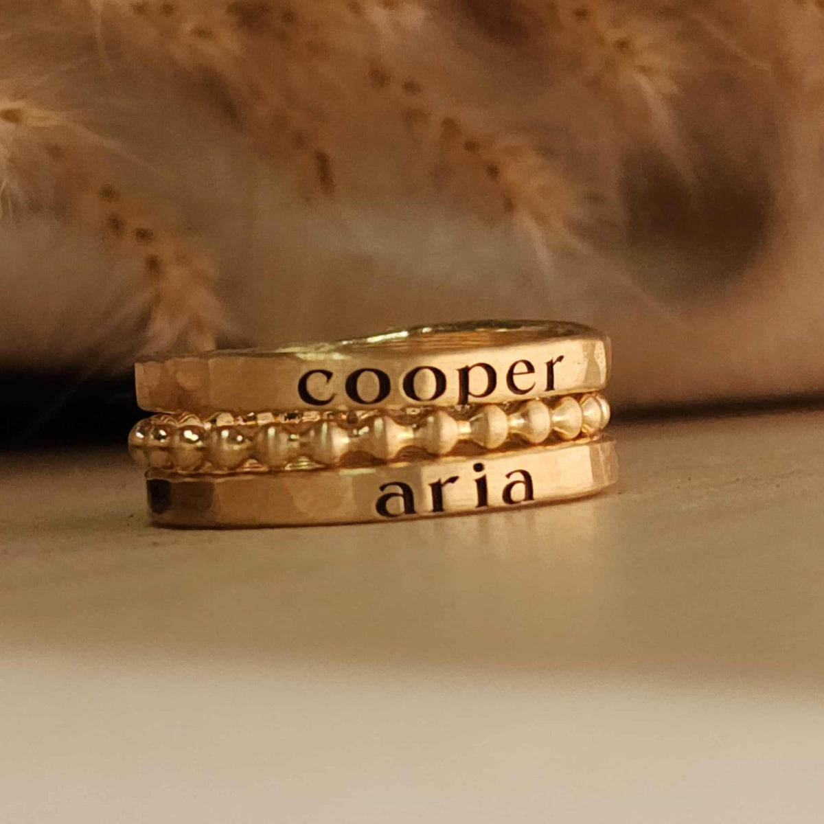The Blake stacking name ring set in 14K gold, silver, and rose gold with personalized rings and beaded design
