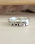 A set of sterling silver rings, including one with a clear cubic zirconia, and two with engraved names in different fonts.