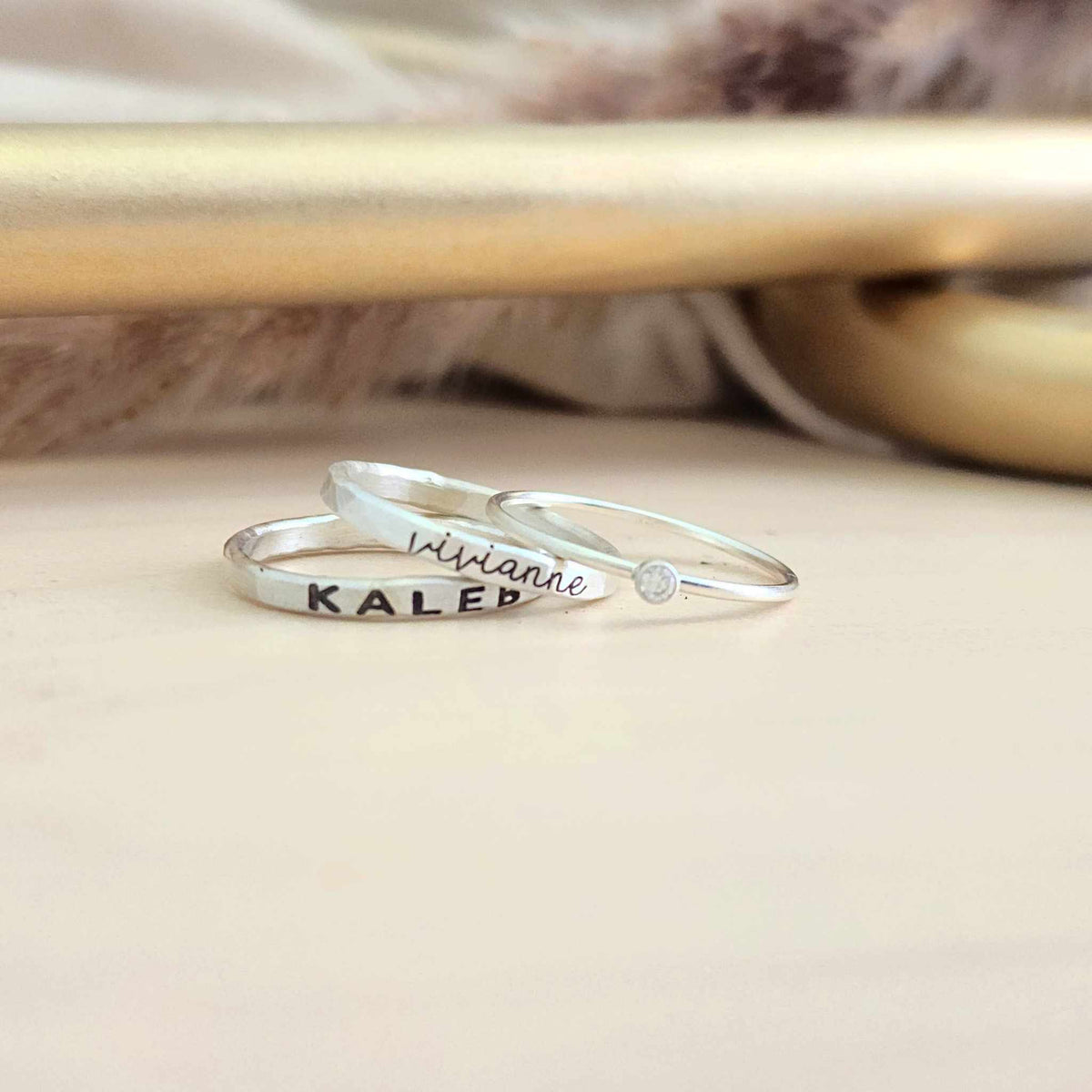 Three silver rings displayed on a wood table
