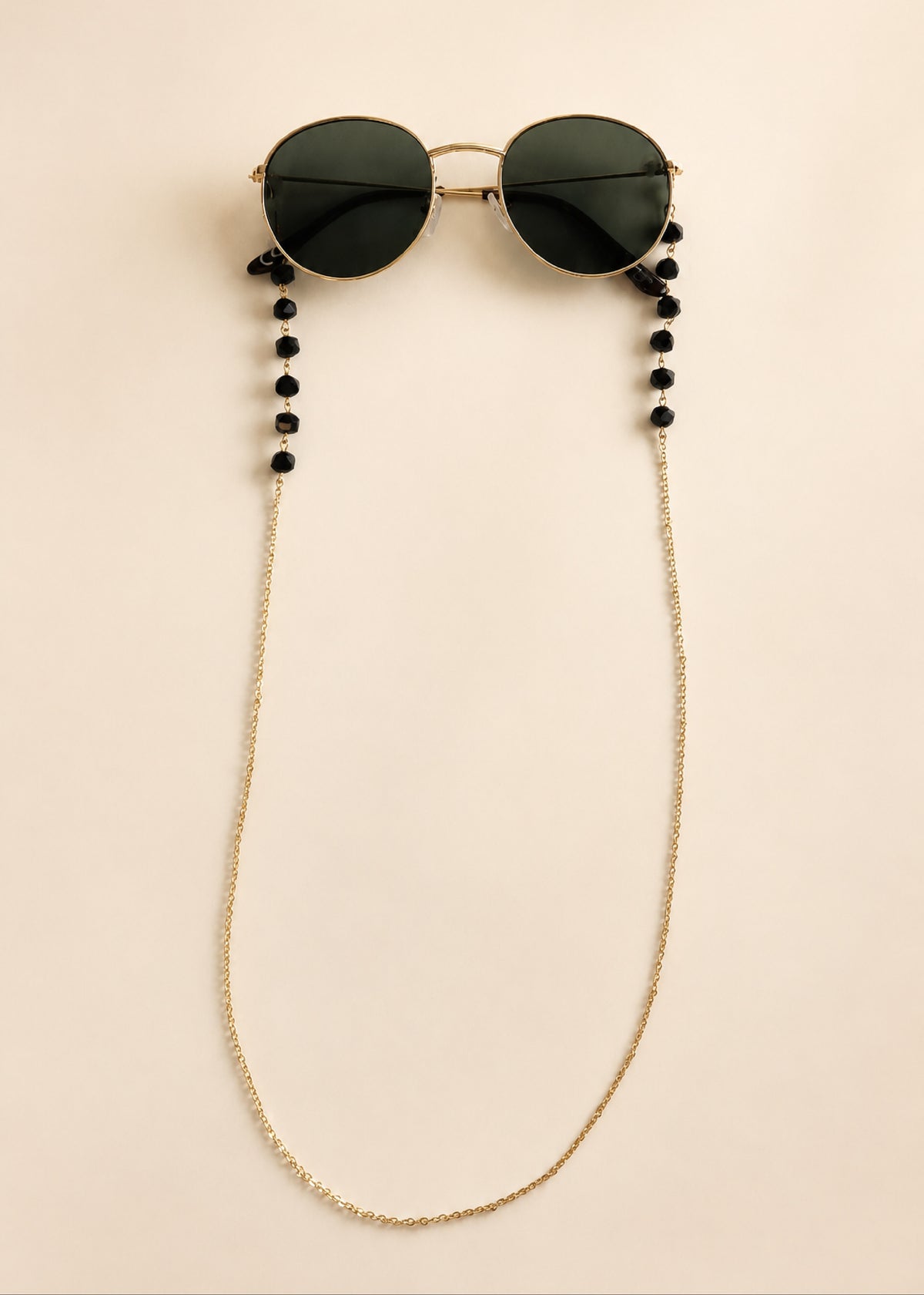 Sunglasses with a beaded chain on a beige background