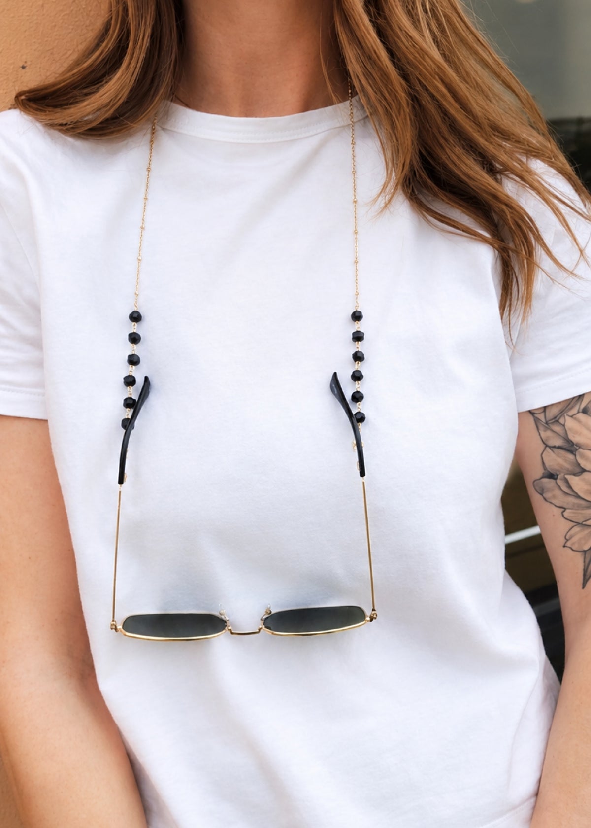 Person wearing a white t-shirt with sunglasses hanging from the neckline.
