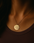 Gold necklace with a round pendant on a dark background
