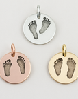 Three round pendants with footprints in silver, rose gold, and yellow gold on a light gray background.