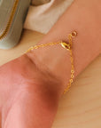 Gold bracelet lobster clasp close up on a wrist with a neutral background