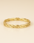Gold braided ring on a beige background