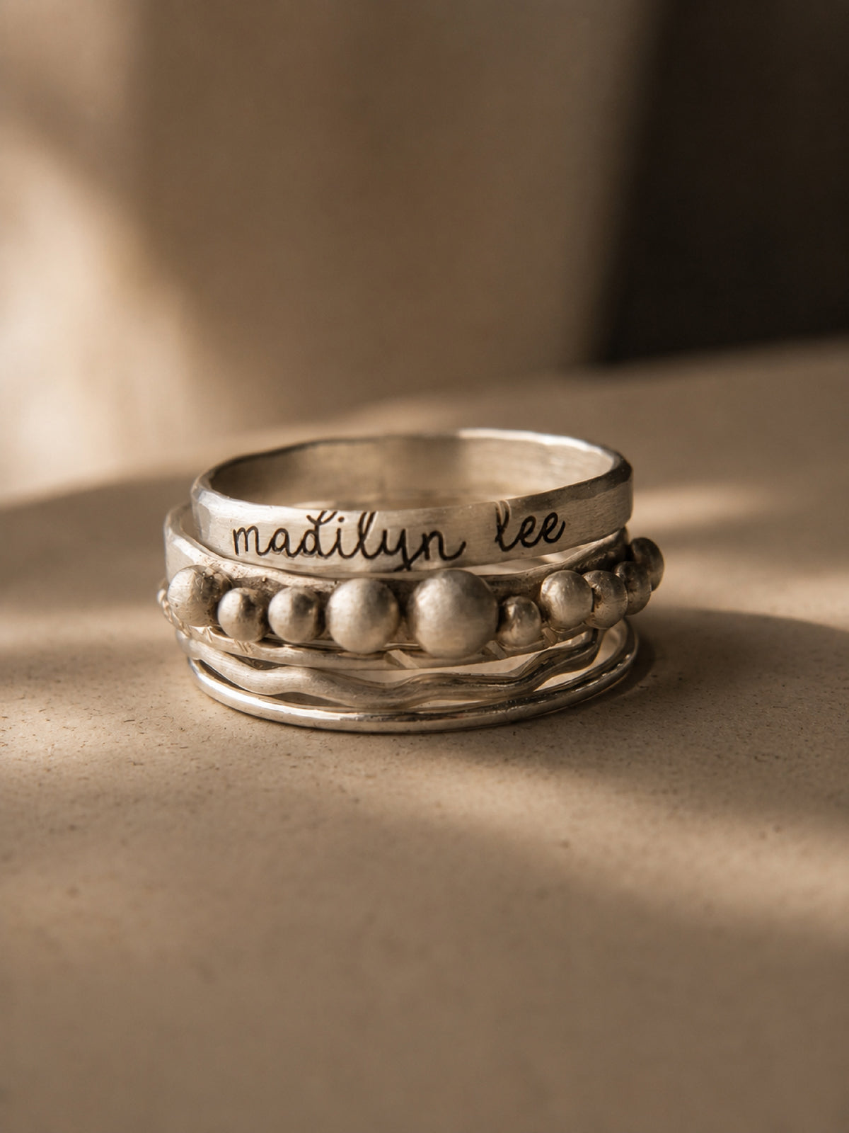 Silver ring with engraved name on a beige surface