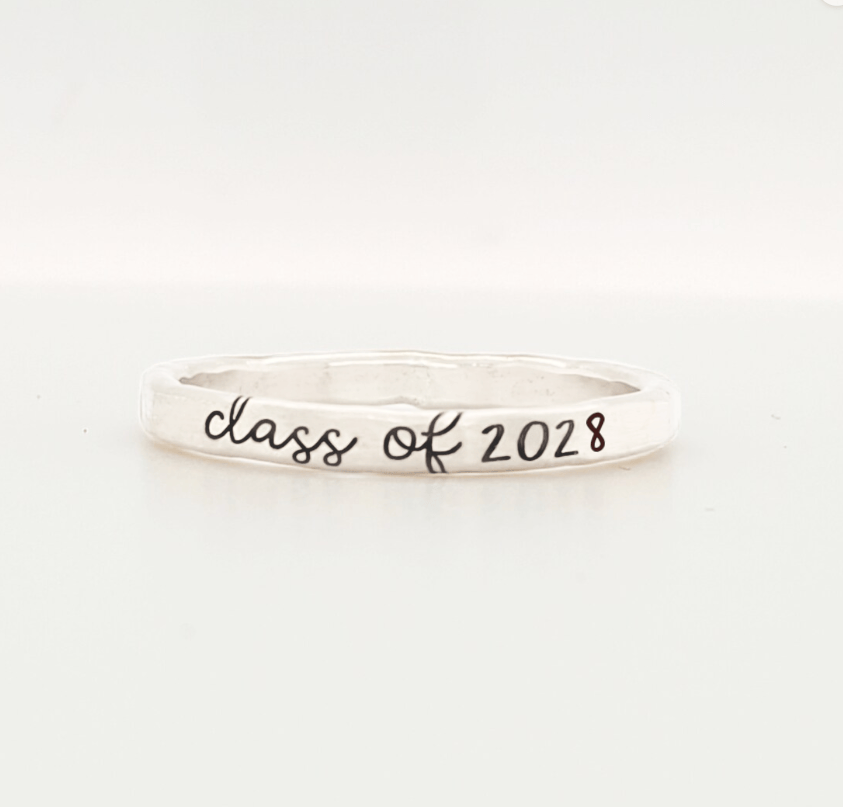 A sterling silver colored stacking ring with 'class of 2028' engraved on it, displayed against a white background.