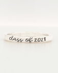A sterling silver colored stacking ring with 'class of 2028' engraved on it, displayed against a white background.
