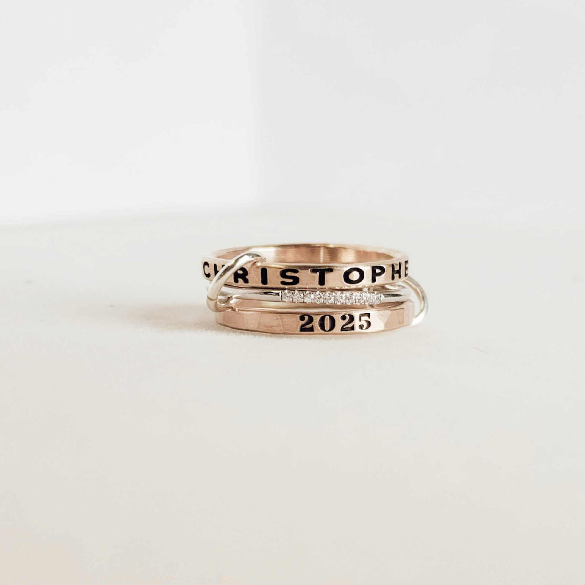 Two gold rings with engraved text on a white background