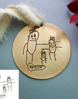 Personalized child art engraved ornament displayed on holiday greenery