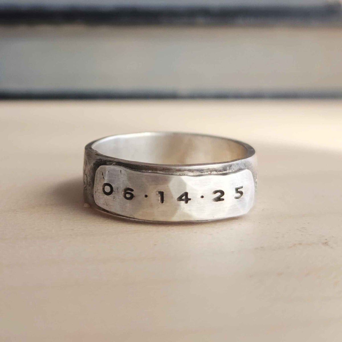 Silver ring with engraved numbers on a wooden surface