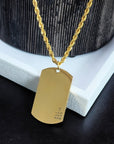 Gold dog tag necklace on a textured surface