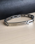 Silver bracelet with engraved names on a beige surface