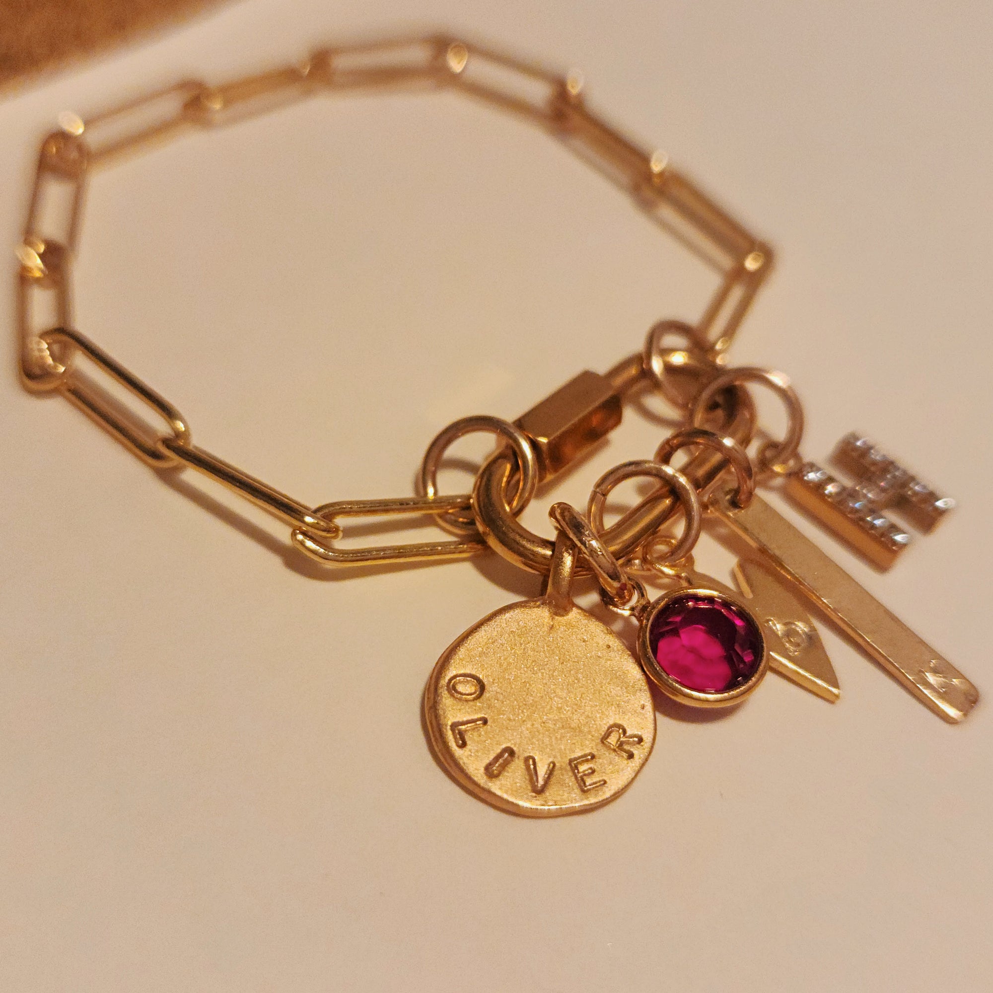 Gold bracelet with various charms on a beige background