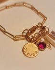 Gold bracelet with various charms on a beige background