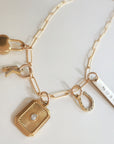 Gold necklace with various charms on a light background