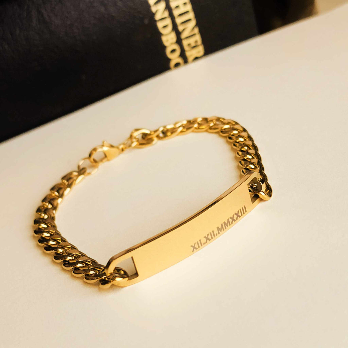 Gold chain bracelet with engraved design on a white surface