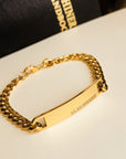 Gold chain bracelet with engraved design on a white surface