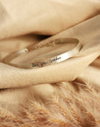 silver cuff bracelet laying on beige materal