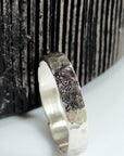 Silver ring with fingerprint design on a textured surface