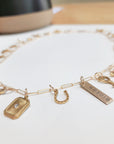 Gold charm bracelet with various charms on a white surface