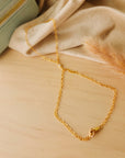 14k Gold-filled hand chain on a wooden surface with a beige fabric background