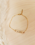 A gold-filled bracelet with a personalized signature tag on a person's wrist, showing the name 'Josephine'.