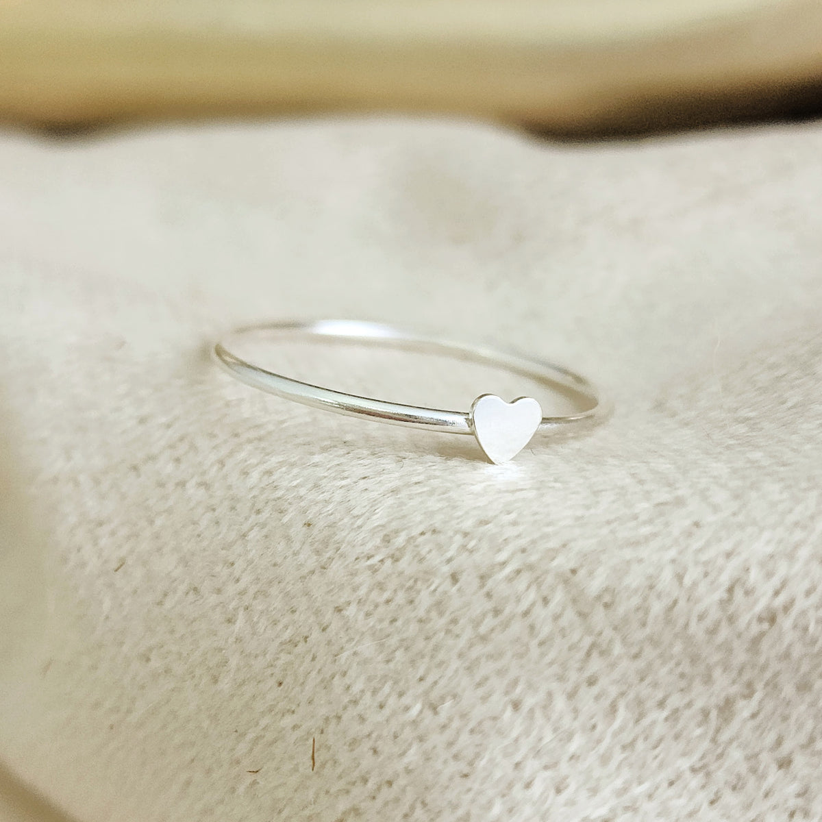 Suggestion
A silver colored mini heart ring placed on a white fabric surface.