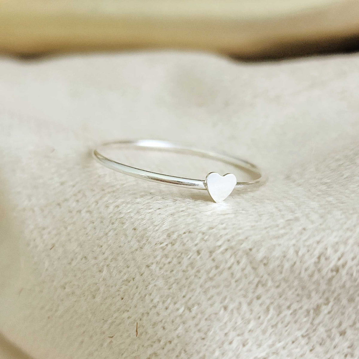 Suggestion
A silver colored mini heart ring placed on a white fabric surface.