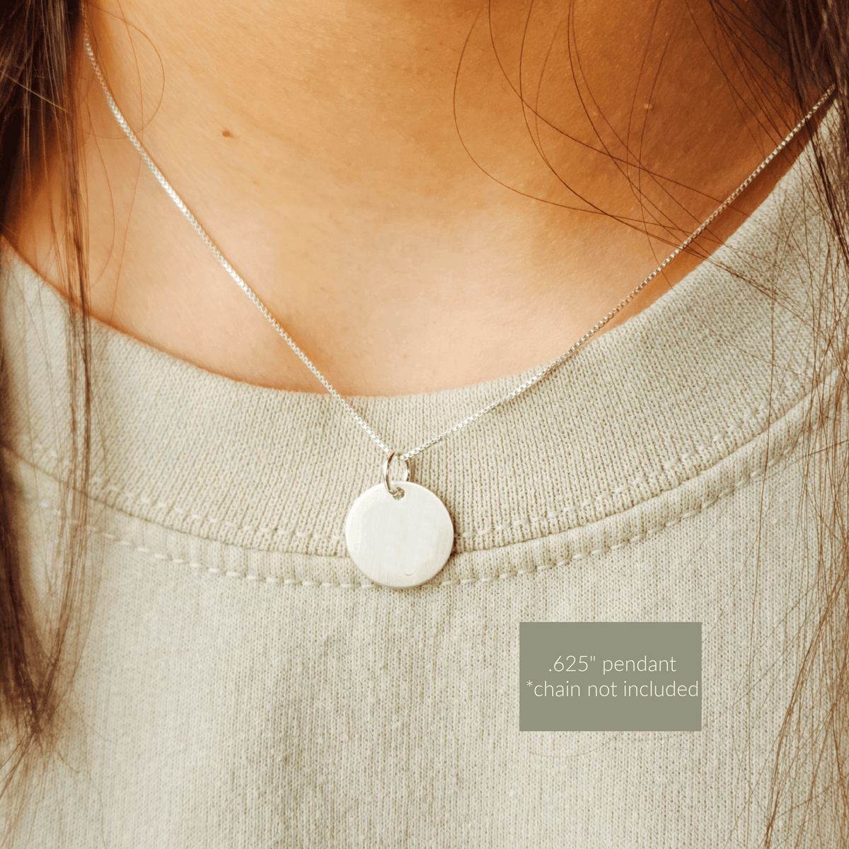Close-up of a silver pendant necklace on a person wearing a light green top.