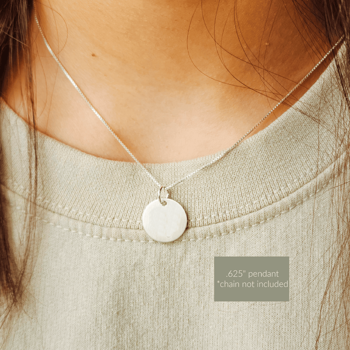 Close-up of a silver pendant necklace on a person wearing a light green top.