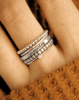five silver rings, one ring is personalized with a name, shown on a woman's hand