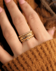 a woman in a brown shirt is holding up her hand, showing her gold ring set