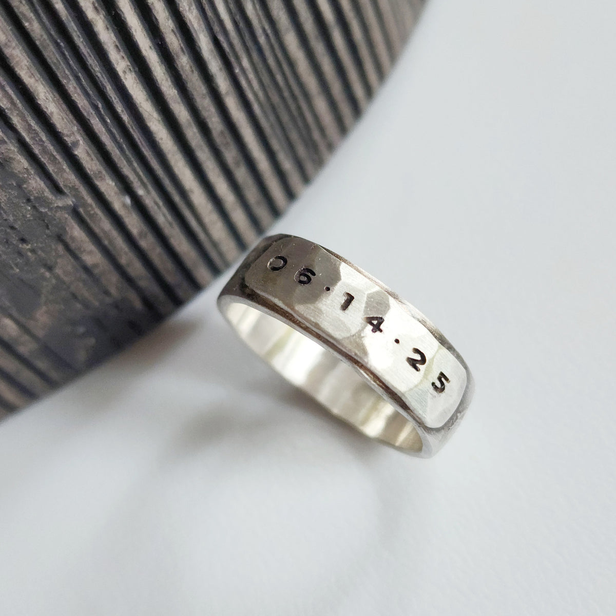 Silver ring with engraved numbers on a textured surface