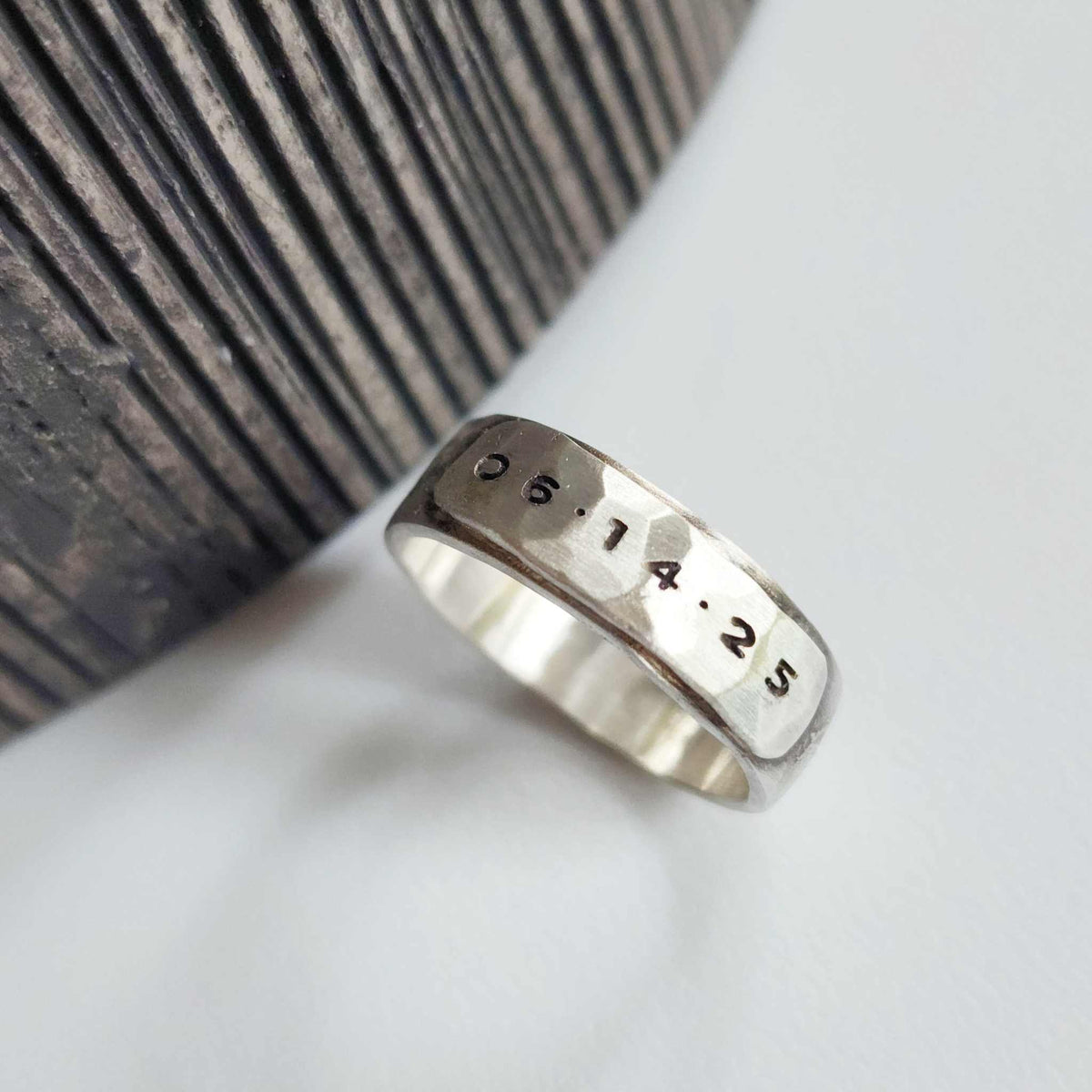 Silver ring with engraved numbers on a textured surface