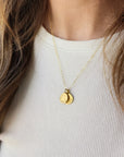 Gold necklace with two round pendants on a white shirt
