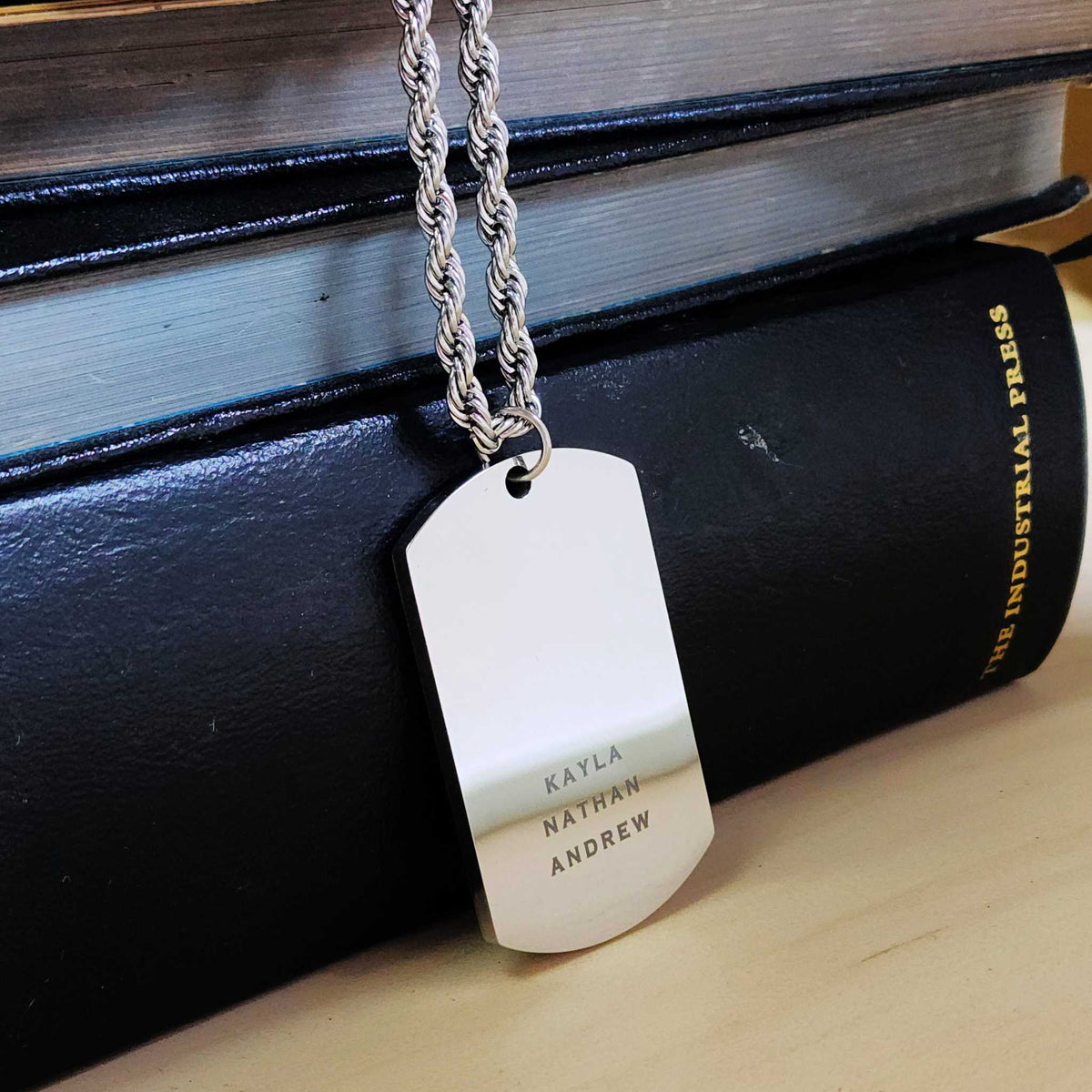 Dog tag necklace with engraved names on a black surface