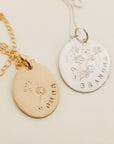 Two necklaces with gold-filled or silver round charms, one with a floral design and the other with a more detailed floral wreath design, attached to small gold or silver chains.