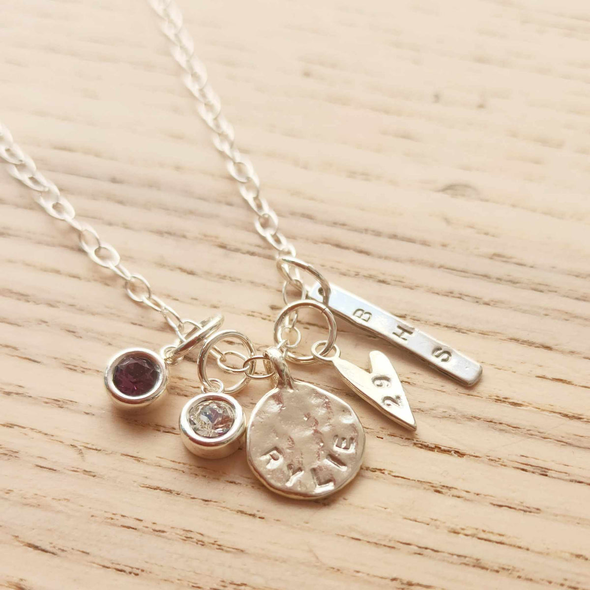Silver necklace with various charms on a wooden surface