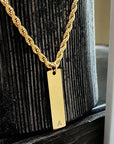 Gold necklace with a rectangular pendant on a wooden surface